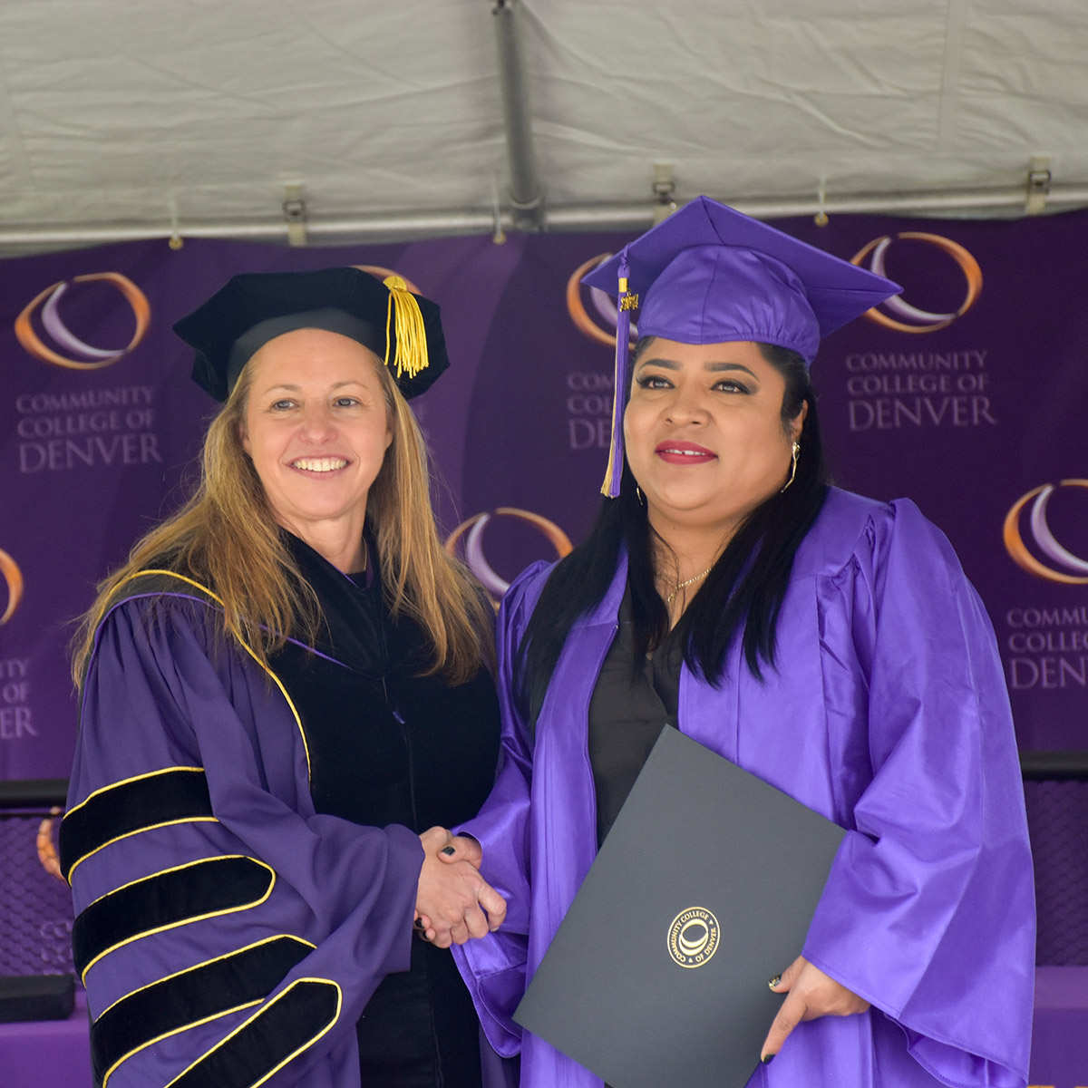 CCD President, Dr. DeSanctis, shaking hands with a female graduate