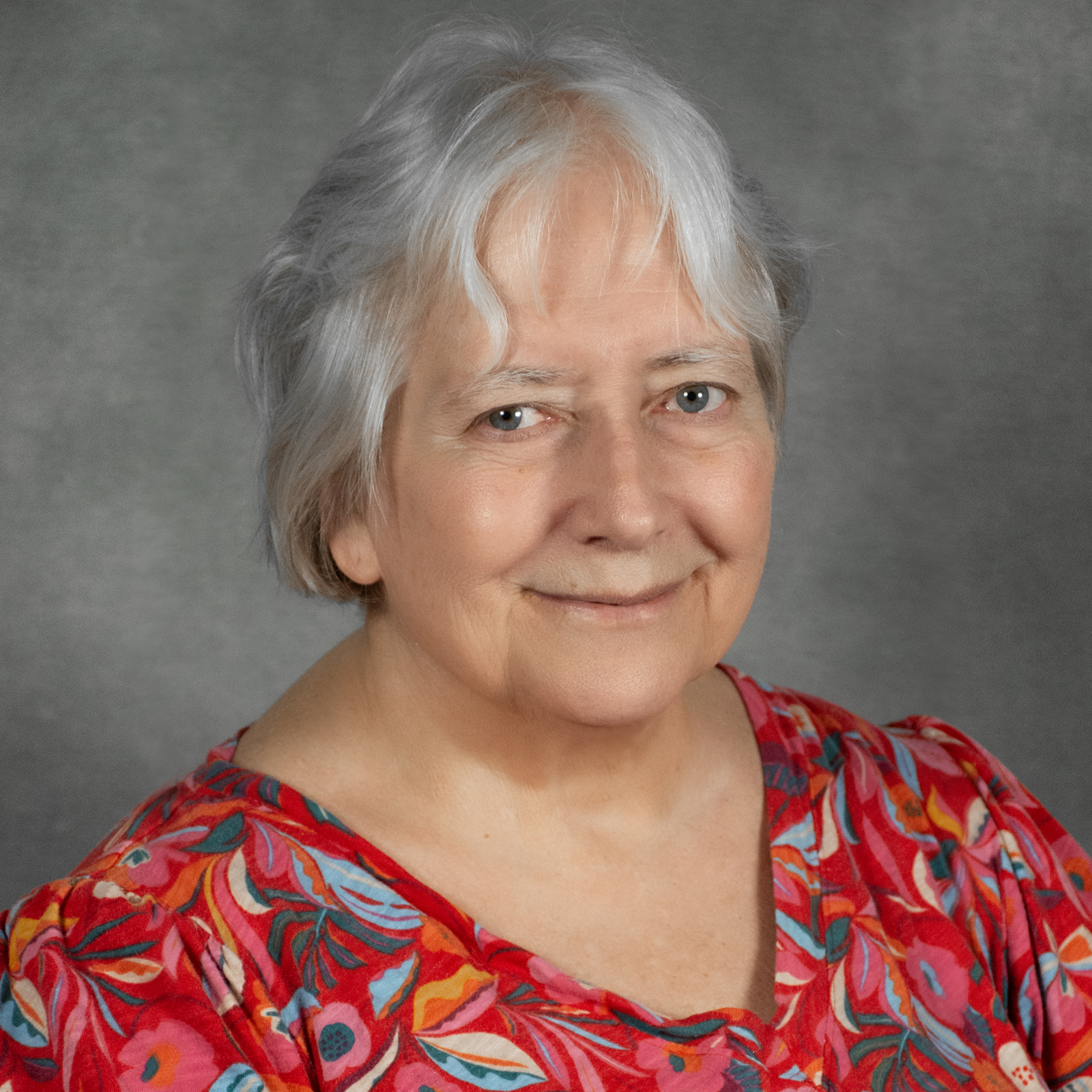 woman with short silver hair wearing red print top