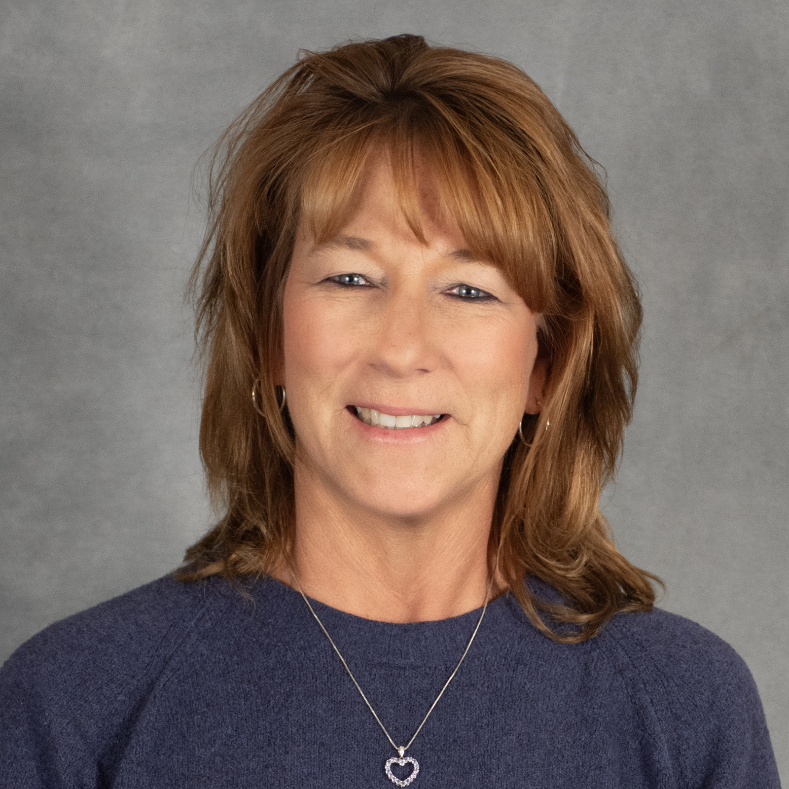 Woman with medium length red hair wearing a blue sweater