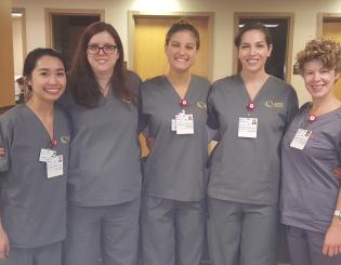 5 young nurse aide students standing in scrubs smiling