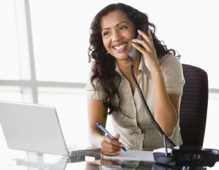 image of young woman answering phones and looking at laptop