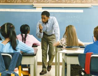 image of male elementary school teacher in front of classroom teaching