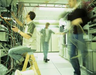 image of three people in a computer server room working on computer cables