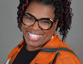black woman wearing glasses in an orange shirt smiling