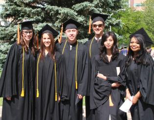 group of male and female graduates in black caps and gowns smiling