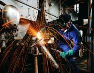 man in a machining helmet working with sparks