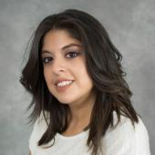 Young female with black waving hair in white shirt.