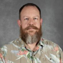 man with full brown beard and short hair wearing floral shirt