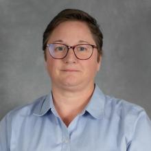 Person with short brown hair wearing glasses and blue shirt