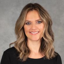 Woman with medium length brown highlighted hair wearing a black top