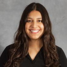 Woman with long dark brown hair wearing a black v-neck top