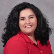 Smiling woman with wavy shoulder length black hair wearing a bright red shirt