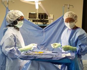 two women in surgical gear practicing in a lab