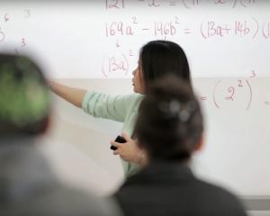 Math teacher at the white board pointing to math equations 