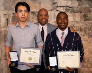 two students holding certificates and awards with the president of the college